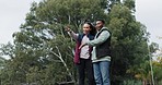 Camping, happy couple and hand pointing to forest, view or nature, relax and talking together. Love, woods and man with woman at a camp site for freedom, vacation and woods experience with scenery 