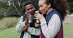 Camping, coffee and couple relax in a forest, happy and talking while bonding in nature. Love, smile and young people at a camp site with tea, freedom and conversation, travel and enjoy adventure
