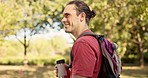 Nature, walking and man hiking in a park for fresh air with a bottle of water and backpack. Adventure, travel and young male person trekking in an outdoor green environment with a positive mindset.