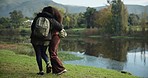 Women, hug or walking by nature lake for camping trip, travel or relax adventure break. Back, bonding or lgbtq couple of friends in embrace by forest, wood or hiking by water in holiday date trekking