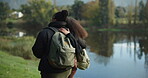 Couple of friends, hug or walking by nature lake for camping trip, travel or relax adventure break. Back, bonding or lgbtq women in embrace by forest, wood or hiking by water in holiday date trekking