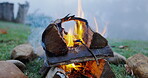 Fire, camp and wood in nature for travel in outdoor for vacation with grass in closeup. Wood, flames and bonfire for camping in environment with smoke for barbecue during travel for survival in park.