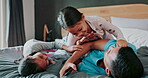 Family, fun and a father playing with his children in the bedroom of their home together while bonding in the morning. Smile, laughing and girl kids on a bed with their dad for comedy or games