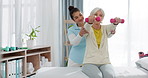 Senior woman with a dumbbell, nurse and physiotherapy in clinic for rehabilitation, fitness and support in healthcare exercise. Physical therapy, help and training with a physiotherapist in hospital