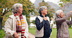 Senior friends, talking and walking together on an outdoor path to relax in nature with elderly women in retirement. Happy, people pointing and conversation in the park or woods in autumn or winter