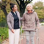 Senior woman, walker and nurse outdoor in a park with healthcare for ...