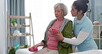 Senior woman, physiotherapy with dumbbell and nurse in clinic for rehabilitation, help and support in healthcare exercise. Physical therapy, fitness and training with a physiotherapist in hospital