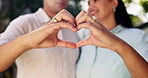 Smile, couple and heart hands outdoor for care, affection and romance together. Man, woman and love sign for trust, support and commitment in marriage for loyalty, kindness and emoji for partnership