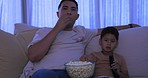 Movie, father and boy on a couch, popcorn and relax with happiness, quality time and bonding. Family, dad and male parent with kid, child or watching a film on the weekend, home and break with snacks