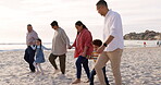 Big family, holding hands and walking on beach for vacation, holiday or adventure. Men, women or parents and grandparents with children at ocean for quality time with love and care outdoor in nature