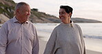 Senior couple, beach and walking outdoor at sunset for love, care and quality time on travel. Happy man and woman holding hands at ocean for retirement holiday or vacation while talking in nature