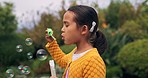 Park, child and girl blowing bubbles, happy and enjoying fun time with joy, summer break and childhood development. Outdoor, freedom and female kid learning, playing with soap bubble toy and wand