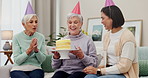 Birthday party, cake or wow and senior woman making a wish with friends in the home living room to blow out candles. Celebration, applause or milestone with an old person enjoying a retirement event