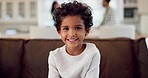 Face, smile and boy child on a sofa, playful and cute with parents in their home for family time. Happy, portrait and sweet kid chilling in a living room on the weekend for fun, resting and playing