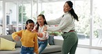 Happy, fun and mother dancing with her children to music in the living room of their family home. Happiness, bonding and young mom moving and jumping with her girl kids to a song, playlist or radio.