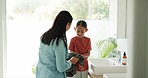 Mother dry the hands of her child in the bathroom of their modern family home together. Hygiene, teaching and young mom helping her girl kid while washing skin to prevent germs or bacteria at home.