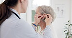 Female doctor, consultation and hearing aid on senior person at clinic for help with problem. Hearing, loss and deaf and installation for elderly woman at appointment with medical professional.