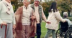 Friends, relax and senior people in park for bonding, wellness and quality time together outdoors. Friendship, wheelchair and happy elderly man and women with caregiver on bench walking in nature