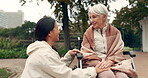 Wheelchair, park and a senior woman with a disability talking to her nurse during a walk together outdoor. Healthcare, medical and a female care chatting to an elderly patient or resident in a garden