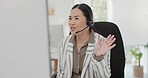 Asian woman, call center and wave in virtual meeting, discussion or customer service at the office. Friendly female person, consultant or agent talking on computer in hello for webinar at workplace