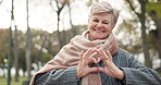 Happy senior woman, heart hands and nature for love, care or romance in outdoor forest or park. Portrait of elderly female person smile with loving emoji, sign or shape in symbol for romantic gesture