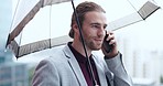 Phone call, raining and businessman with an umbrella in the city while walking to office in urban street. Technology, communication and young professional male person on mobile conversation in town.