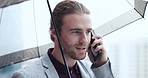 Walking, phone call and man with an umbrella in the city while commuting to his office. Technology, communication and young professional male person on a mobile conversation in a raining urban town.