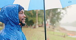 Rain, umbrella and peace with black man in nature for travel, hiking and vacation adventure. Calm, freedom and winter storm with person and relax in countryside woods for health, camping and trekking