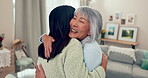 Family, retirement and a senior asian woman hugging her daughter in the living room of a home during a visit. Love, smile and an adult child embracing her happy mother together in an apartment