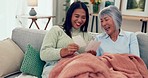 Talking, happy and daughter with mother and pictures on the living room sofa, laughing and bonding. Happy, family and Asian woman speaking to an elderly mom about a memory with a photo on the couch