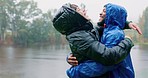 Hiking, love and an interracial couple hugging in the rain while outdoor in nature together for romance or adventure. Smile, freedom or travel with a man and woman camping in wet winter weather