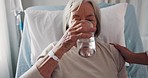 Sick, care and woman drinking water in a hospital after a surgery, healthcare and nutrition. Thirsty, medical and a talking senior patient with a drink from a doctor in a bed for nursing and support