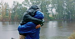 Hiking, freedom and a couple hugging in the rain while outdoor in nature together for romance or adventure. Smile, love or travel with a man and woman bonding while camping in wet winter weather