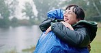 Hiking, love and a couple hugging in the rain while outdoor in nature together for romance or adventure. Smile, freedom or travel with a man and woman bonding while camping in wet winter weather