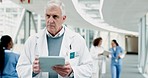 Doctor, senior man and tablet in corridor, reading results analysis and thinking with healthcare in clinic. Male medic, touchscreen or notes in hospital hallway for info, review or medical research