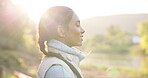 Sunrise, nature and face of woman breathing for morning air, wellness and relax on outdoor journey, travel or adventure. Mindfulness, sunshine peace and profile of Indian person relax, calm and smile