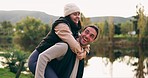 Couple piggyback, happy and in nature for holiday, summer love and playing together. Smile, care and a young man and woman with freedom, quality time and playful by a lake during a camping vacation