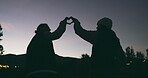 Night sky, heart and silhouette of a couple outdoor in nature with love for travel, adventure or freedom. Back of a man and woman with a shape or icon with hands on holiday, vacation or date in dark