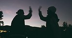 People, high five and celebration at night in city for winning, achievement or milestone together. Silhouette of friends touching hands in late evening for accomplishment, victory or outdoor success 