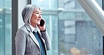 Senior business woman, phone call and window with thinking, contact and networking in office corridor. Mature Asian entrepreneur, CEO or leader with smartphone, talking and communication in Seattle