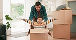 Father, push son and box in new house for games, car or plane with smile, bonding and playful with love. Man, boy child and cardboard for race, speed and excited with care, moving and family home