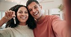 Selfie of happy couple in living room with keys to new home, investment and mortgage for property. Real estate, man and woman with smile, marriage and safety, celebration in dream house for future.