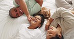 Family, bedroom and tickle in morning with laugh and bonding in a home from above. Young girl, parent love and care in a house on bed with mother, father and daughter together with a happy smile