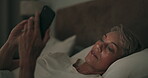 Phone, relax and a senior woman in bed at night, reading a text message for communication. Mobile, social media and evening with an elderly female pensioner lying alone in the bedroom of her home
