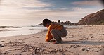 Beach, travel and boy kid playing in the sand while on a tropical vacation, adventure or holiday. Playful, exploring and young child having fun by the ocean or seaside at sunset on a weekend trip.