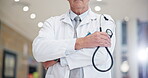 Hands with stethoscope, doctor and man with arms crossed in hospital with bokeh lens flare. Confidence, medical professional and surgeon with cardiology tools for healthcare and wellness in clinic