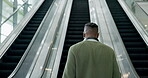 Escalator, walking and back of a business man in a airport for travel, commute and company trip. Headphones, stairs and male professional in a convention center and lobby ready for work seminar