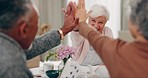 High five, retirement and senior friends at a tea party together during a visit in a home for bonding. Poker, community and support with a group of elderly people playing cards at a social gathering