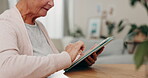 Hands, tablet and a senior woman in her home, feeling nostalgic while scrolling through social media. Technology, internet and an elderly person at a table in her house during retirement closeup