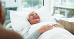 Happy, senior woman and bed in hospital, clinic and talking to therapist, doctor or specialist in healthcare, medicine or care. Elderly person, smile and laugh with medical nurse or nursing home